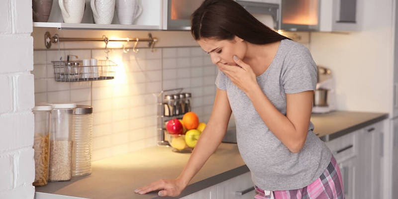 A pregnant woman is having morning sickness in her kitchen