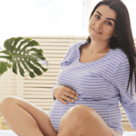 3rd trimester pregnant woman sitting on bed