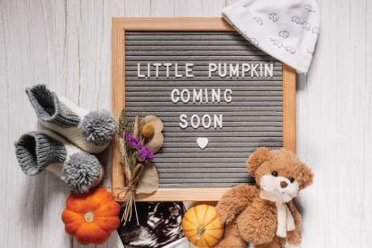 Letter board that reads "Little Pumpkin Coming Soon" surrounded by a baby hat, shoes, bear, sonogram, and pumpkins.